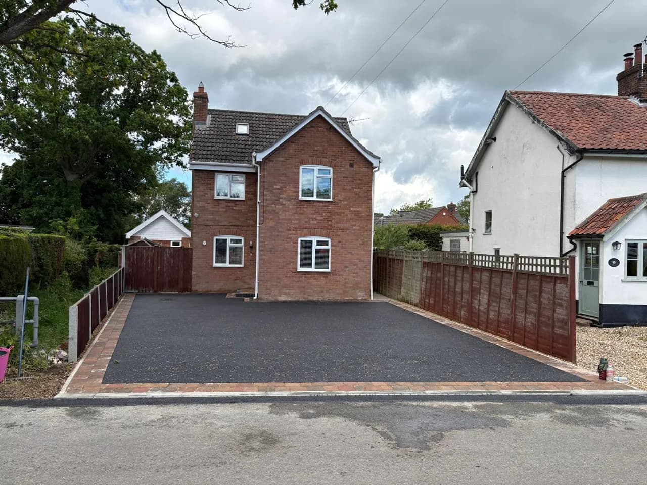 Finished black-surfaced driveway in front of a brick house