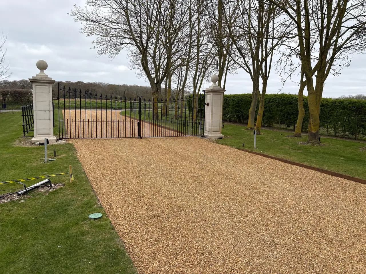 Golden stone private access drive leading to metal gates