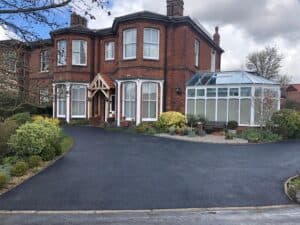 Black asphalt driveway in front of a Victorian house